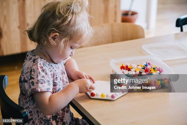 blond girl playing with pegboard game on table at home - white bead stock pictures, royalty-free photos & images