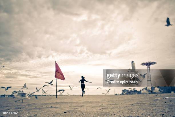 woman running through a flock of seagulls - coney island 個照片及圖片檔
