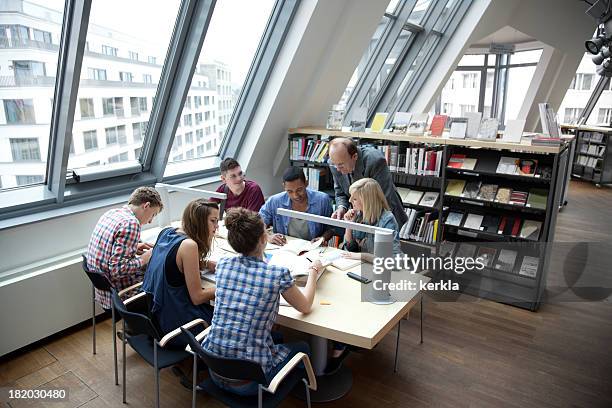 students learning together with teacher in a library - german culture stockfoto's en -beelden