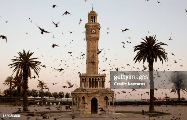 izmir clock tower surrounded by flock of birds at dusk - izmir stock pictures, royalty-free photos & images