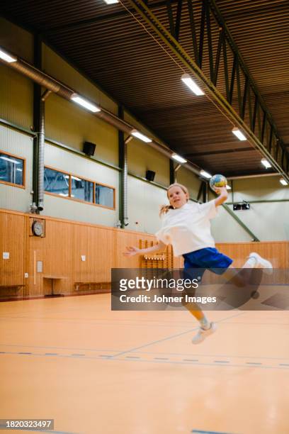 girl jumping while throwing handball in sports court - västra götaland county stock pictures, royalty-free photos & images