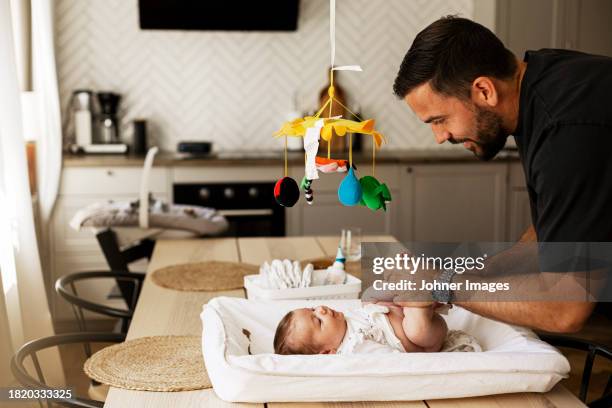 father changing diaper of son lying down on table at home - vaterschaft stock-fotos und bilder