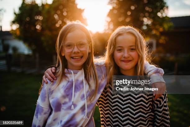 portrait of happy female friends with arms around at sunset - västra götaland county stock pictures, royalty-free photos & images