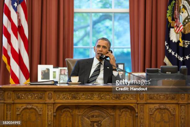 In this handout photo provided by the White House, President Barack Obama speaks with President Hassan Rouhani of Iran during a phone call in the...