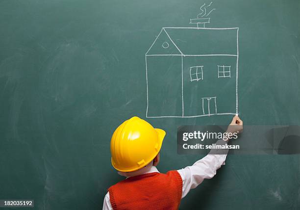 little engineer with helmet drawing a house on blackboard - architekt helm plan stock pictures, royalty-free photos & images