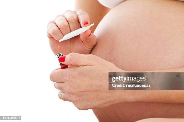 a pregnant woman holding a joint in front of her belly  - drugsmisbruik stockfoto's en -beelden