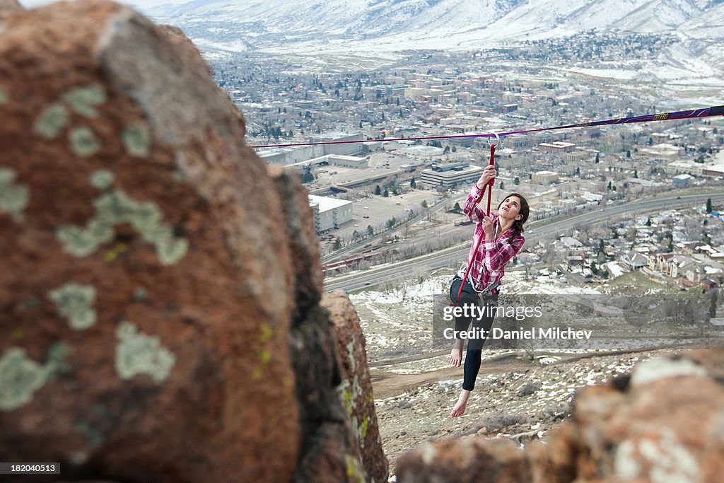 Girl hanging off of a high line, over a small town