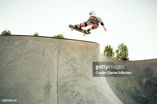 young skateboarder jumping at a skate park. - skatepark stock-fotos und bilder