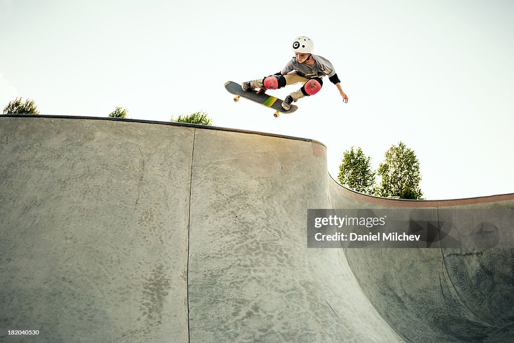 Young skateboarder jumping at a skate park.