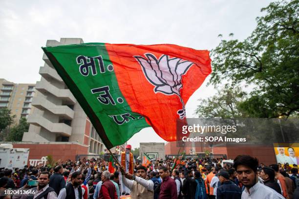 Supporter seen waving the party flag while celebrating the victory in the Madhya Pradesh, Chhattisgarh, and Rajasthan Assembly elections at the BJP...