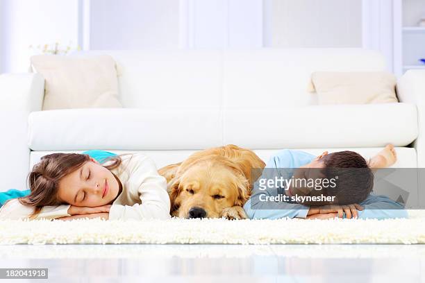 two cute children and dog sleeping down on white carpet. - dog lying down stock pictures, royalty-free photos & images