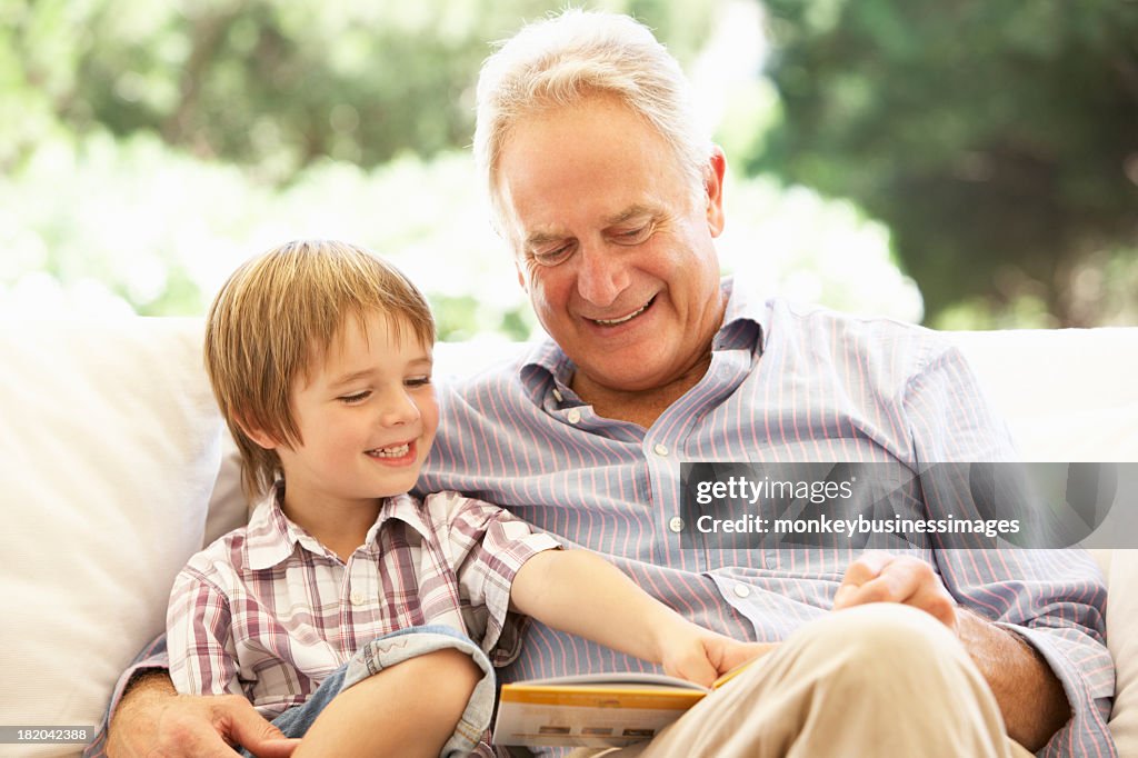 Grandfather With Grandson Reading On Sofa