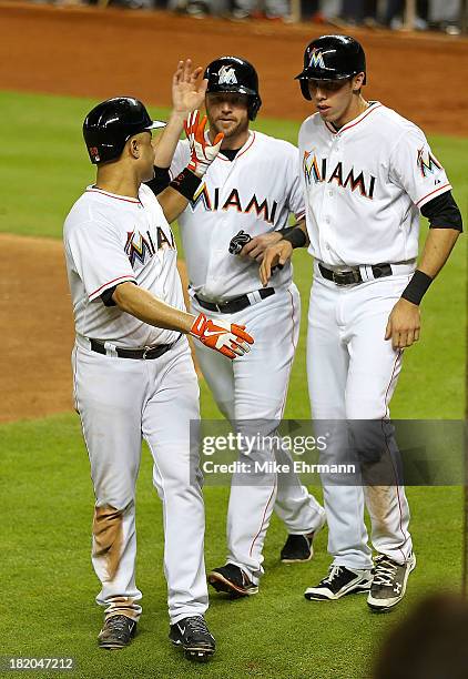 Placido Polanco, Christian Yelich, and Koyie Hill of the Miami Marlins score pn a double by Giancarlo Stanton during a game against the Detroit...