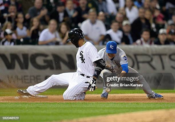 Alexei Ramirez of the Chicago White Sox slides safely into third base with a triple as third baseman Jamey Carroll of the Kansas City Royals loses...