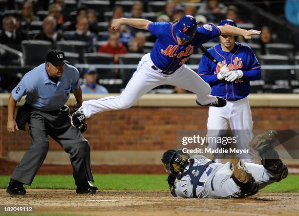 Daniel Murphy of the New York Mets jumps over Martin Maldonado of the Milwaukee Brewers in an attempt to score during the sixth inning on September...