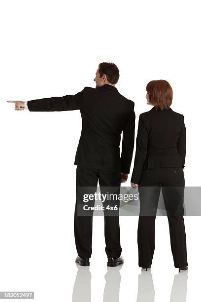 businessman standing with businesswoman and pointing sideways - well dressed couple isolated stock pictures, royalty-free photos & images