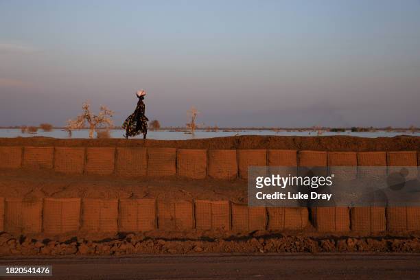 Woman walks along a dyke protecting Internally Displaced Persons , and their host community, from further flooding on November 28, 2023 in Bentiu,...