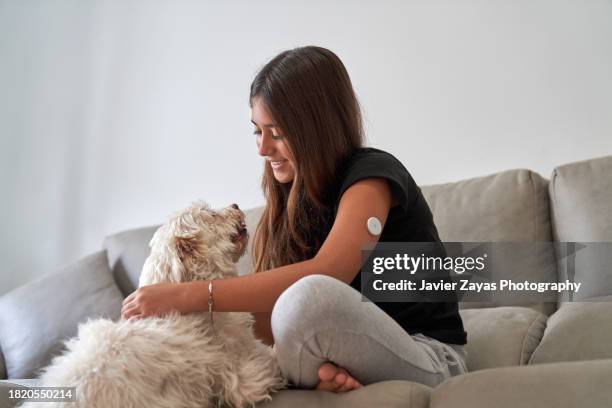 teenage girl playing with her dog at home - continuous glucose monitor stock pictures, royalty-free photos & images
