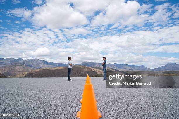 men standing face to face by rows of safety cones with arms crossed - division 2 個照片及圖片檔