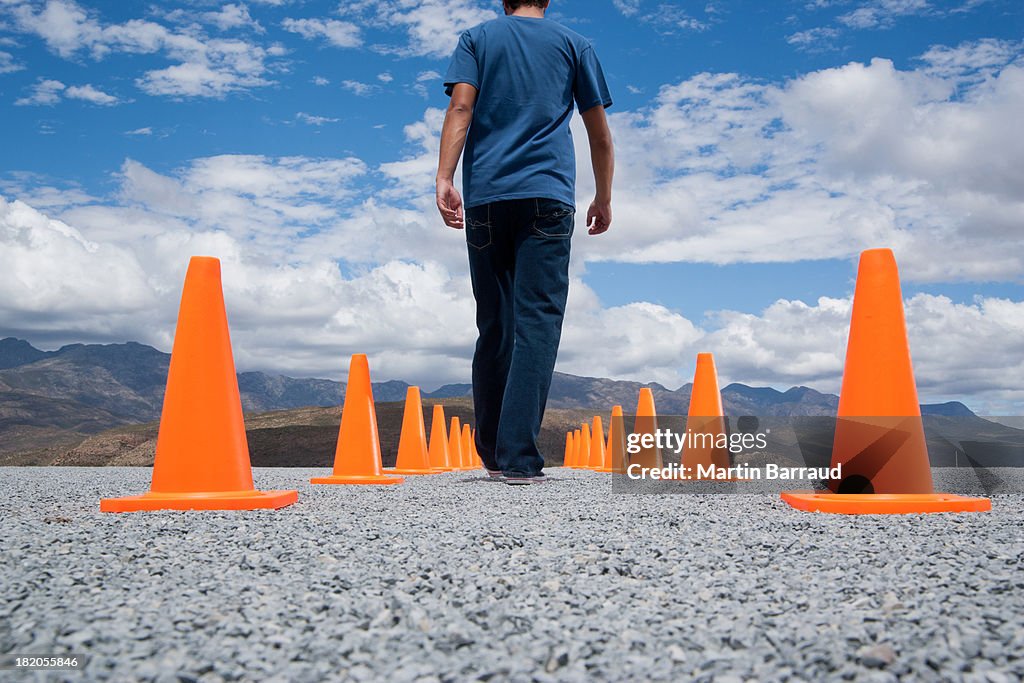 Hombre caminando en entre dos filas de conos de seguridad