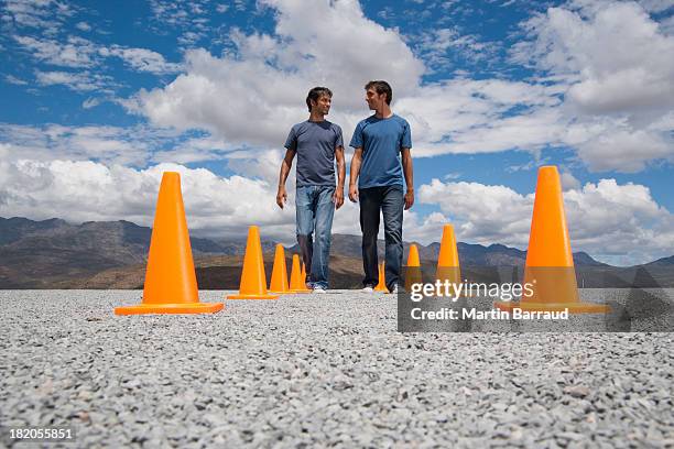 two men walking by each other flanked by two rows of safety cones - safety cone stock pictures, royalty-free photos & images