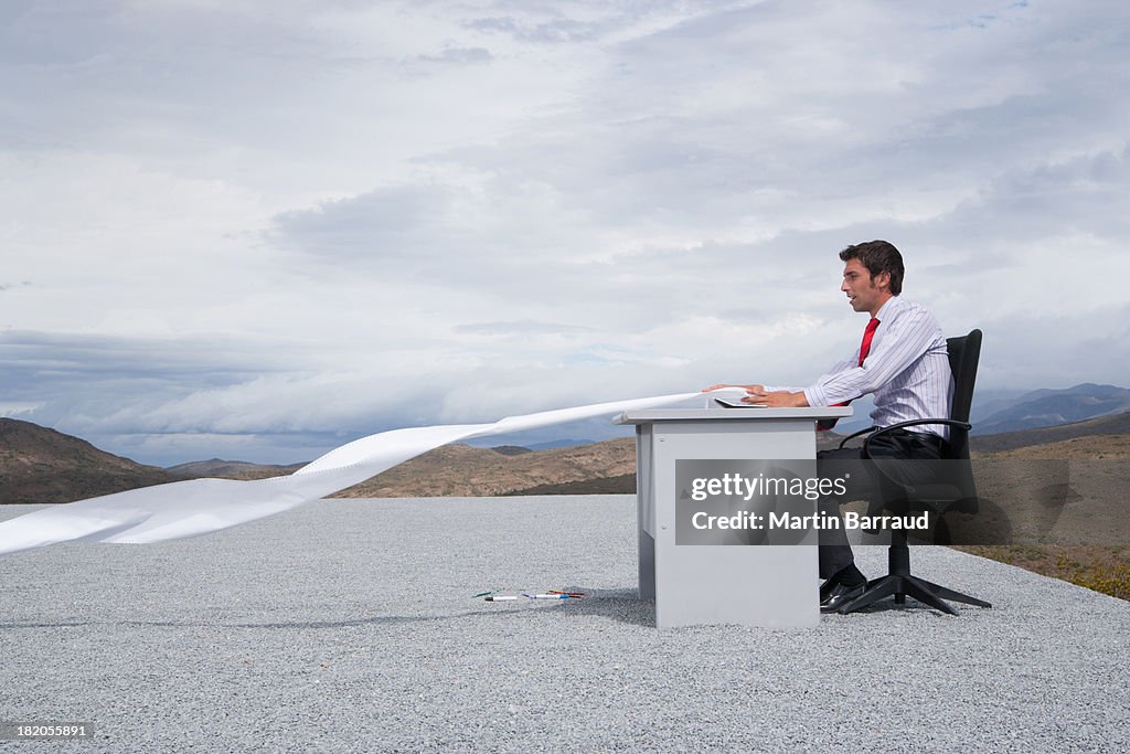 Man working outdoors with papers blowing in the wind