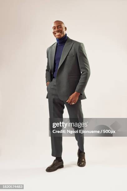 portrait of confident businessman wearing suit standing against white background,nigeria - schwarzer anzug stock-fotos und bilder