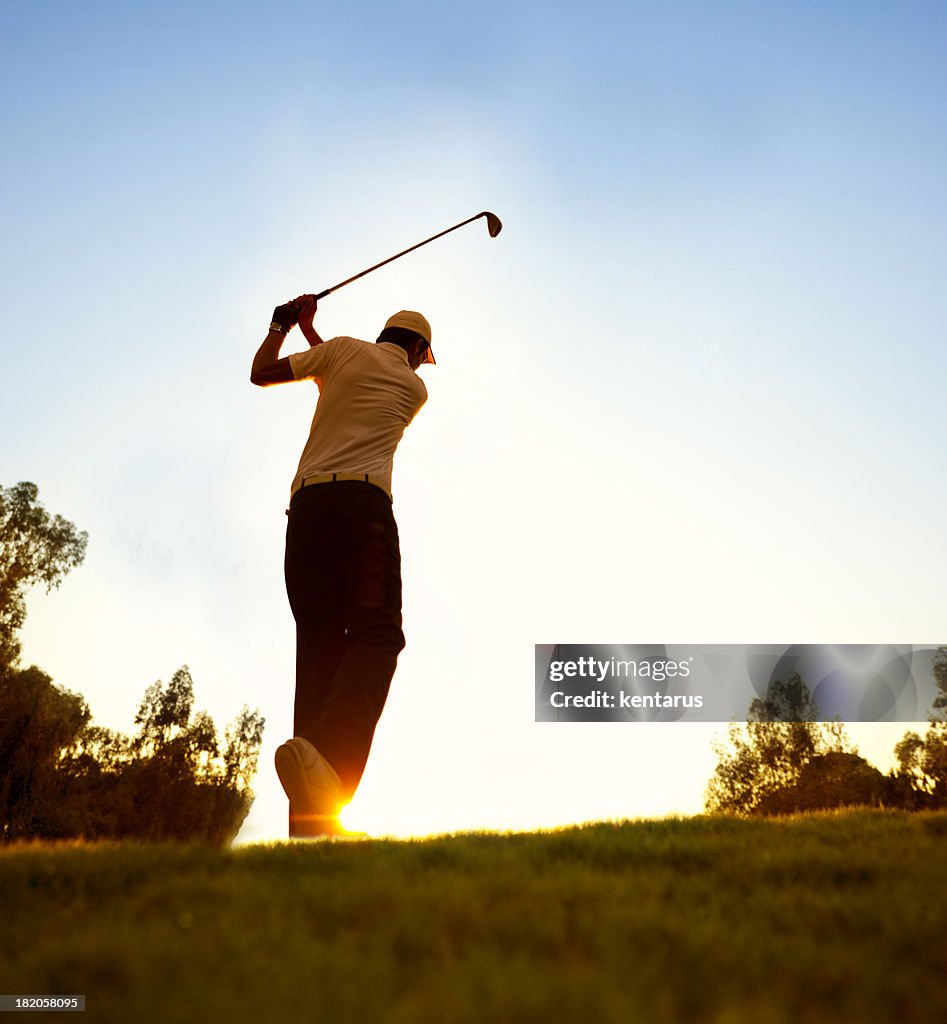 Golfer swinging at beautiful sunset