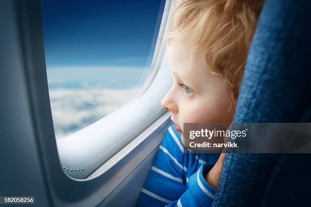 boy watching sky through the airplane window - raamplaats stockfoto's en -beelden