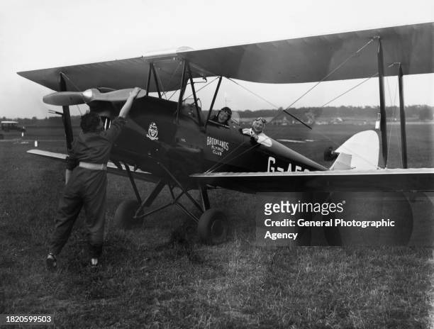 Mona Friedlander turns the propeller as Dorothy Kay and Mrs Ogden sit in a Brooklands Flying Club de Havilland DH-82 Tiger Moth , at Brooklands...