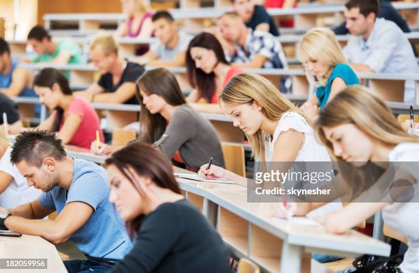 large group of students writing in notebooks. - universiteit stockfoto's en -beelden
