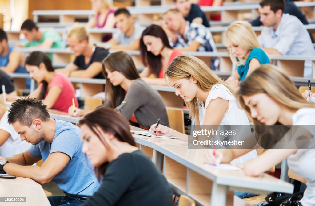 Large group of students writing in notebooks.