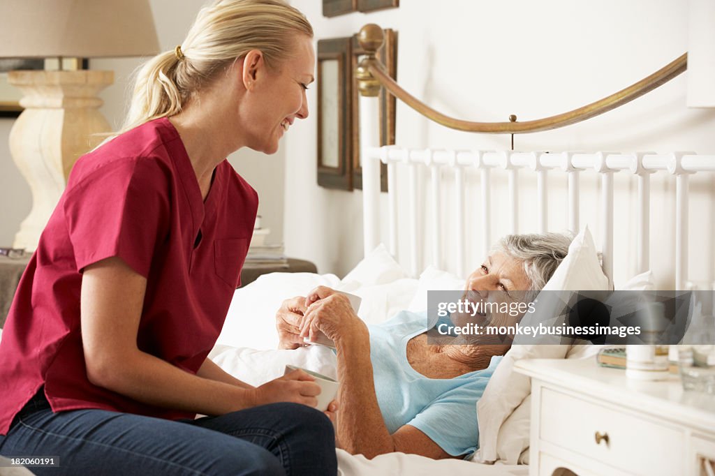 Health Visitor Talking To Senior Woman Patient In Bed