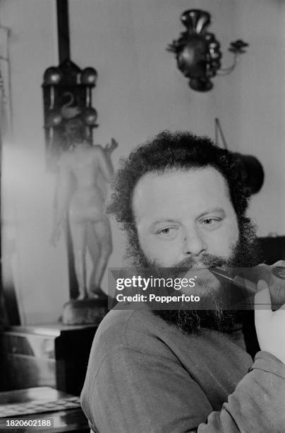 German artist and sculptor Jack Bilbo smokes a pipe in his studio in the garage of his home 'Bilbo Bay' near the town of Weybridge in Surrey, England...