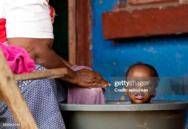 grandmother gives her granddaughter a bath in rural south africa - grandma bathing baby stock pictures, royalty-free photos & images