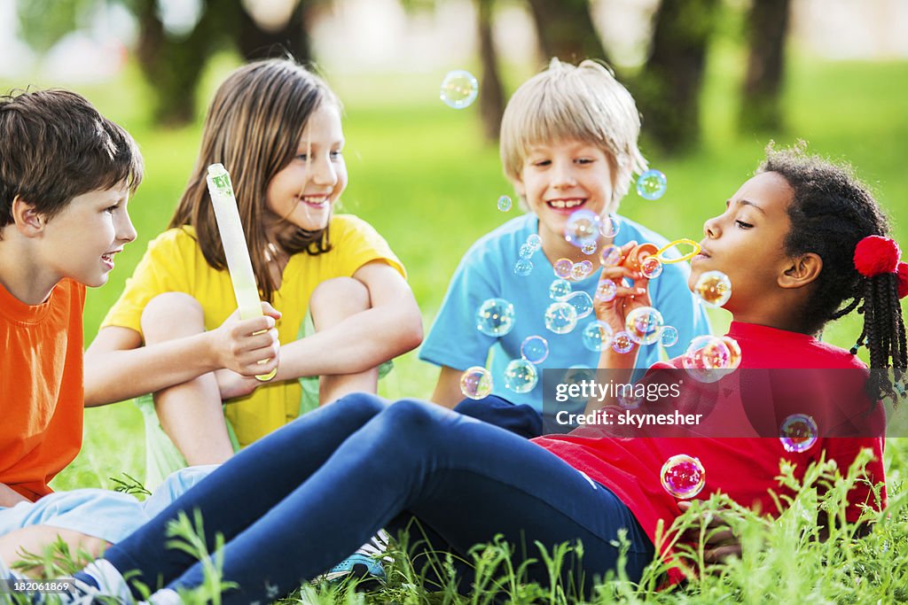 Cute kids blowing bubbles in a park.