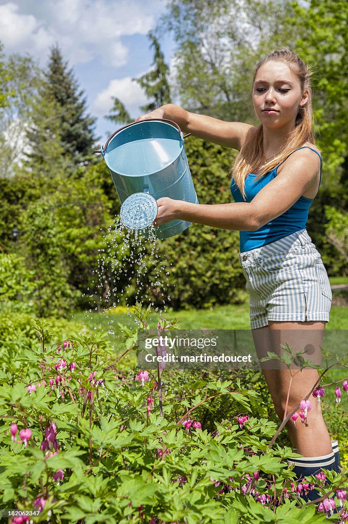 Girl gardening watering plants in a flower bed.