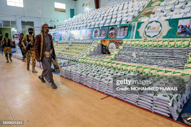 Yemeni man walks past food supplies provided by the Huthi-run Zakat charity authority to be distributed to those in need in Sanaa on December 4, 2023.