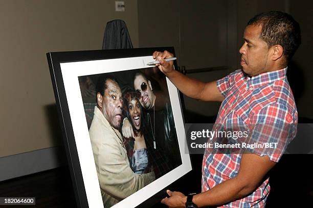 Photographer Johnny Nunez signs one of his photographs at the BET Music Matters "Press Play" event Powered by Monster at TWELVE Atlantic Station on...