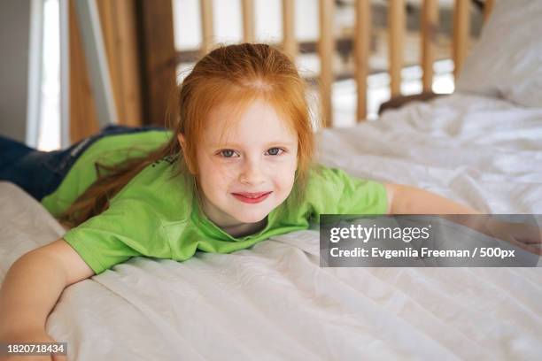 portrait of smiling girl lying on bed at home - junior girl models stock pictures, royalty-free photos & images