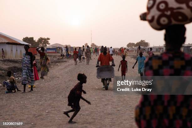 People walk through an Internally Displaced Persons camp on November 29, 2023 in Bentiu, South Sudan. Climate change has divided South Sudan into...