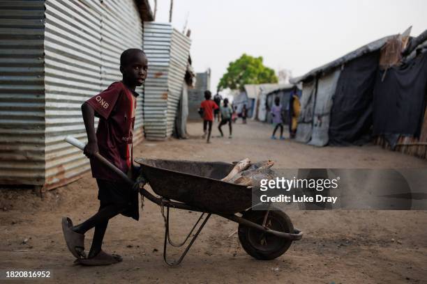 Young boy pushes fish through an Internally Displaced Persons camp using a wheelbarrow on November 29, 2023 in Bentiu, South Sudan. Climate change...