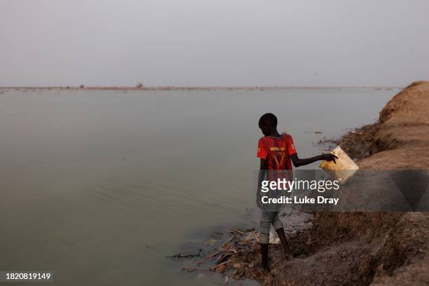 Boy fetches water from over a dyke protecting Internally Displaced Persons , and their host community, from further flooding on November 29, 2023 in...