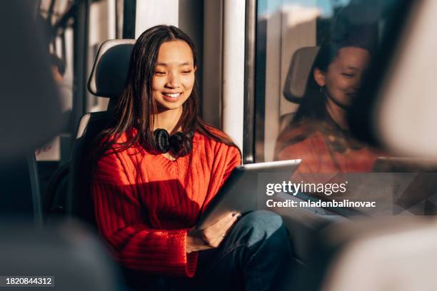 femme asiatique heureuse assise dans un train rapide - métro transport ferroviaire photos et images de collection