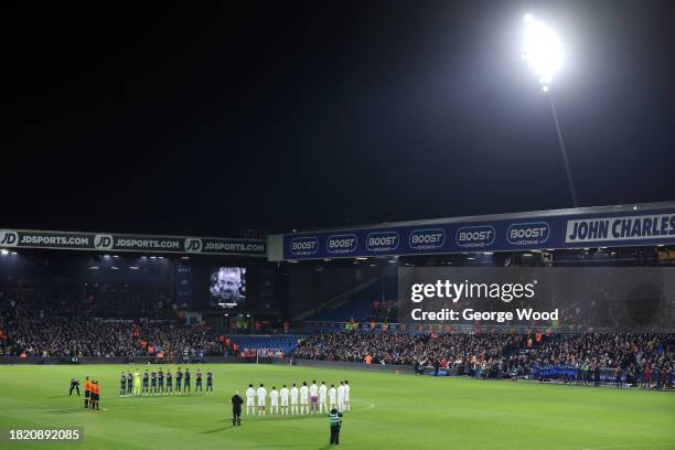 The players, fans and match officials pause for a minutes applause following the recent passing of former English football player and manager, Terry...