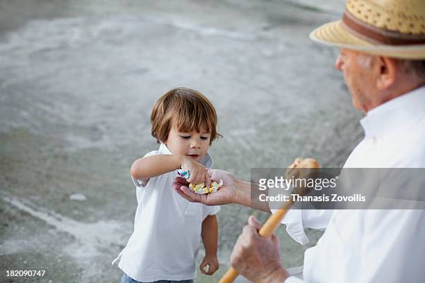 grandfather gives candy to his grandson - nonni bastone foto e immagini stock