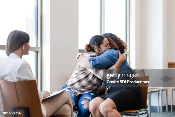 une thérapeute regarde une mère et sa fille s’embrasser après s’être excusées - pardon photos et images de collection