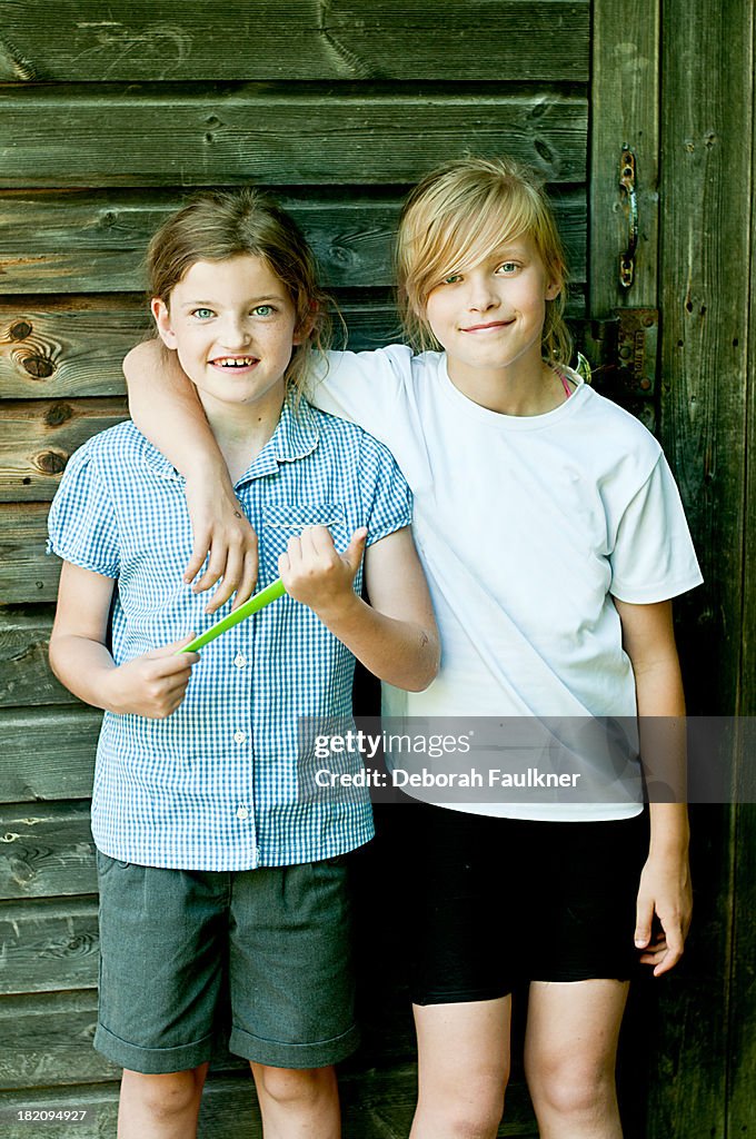 Two girls stood outside against wooden background