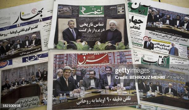 Picture taken on September 28, 2013 in Tehran shows Iranian newspapers with pictures depicting Iranian President Hassan Rouhani, US President Barack...