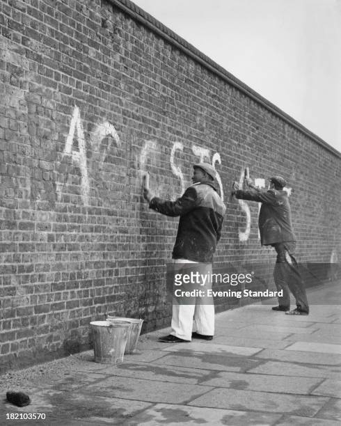 Two workmen clean anti-Apartheid graffiti from the wall at Lords Cricket Ground, London, 2nd February 1970.